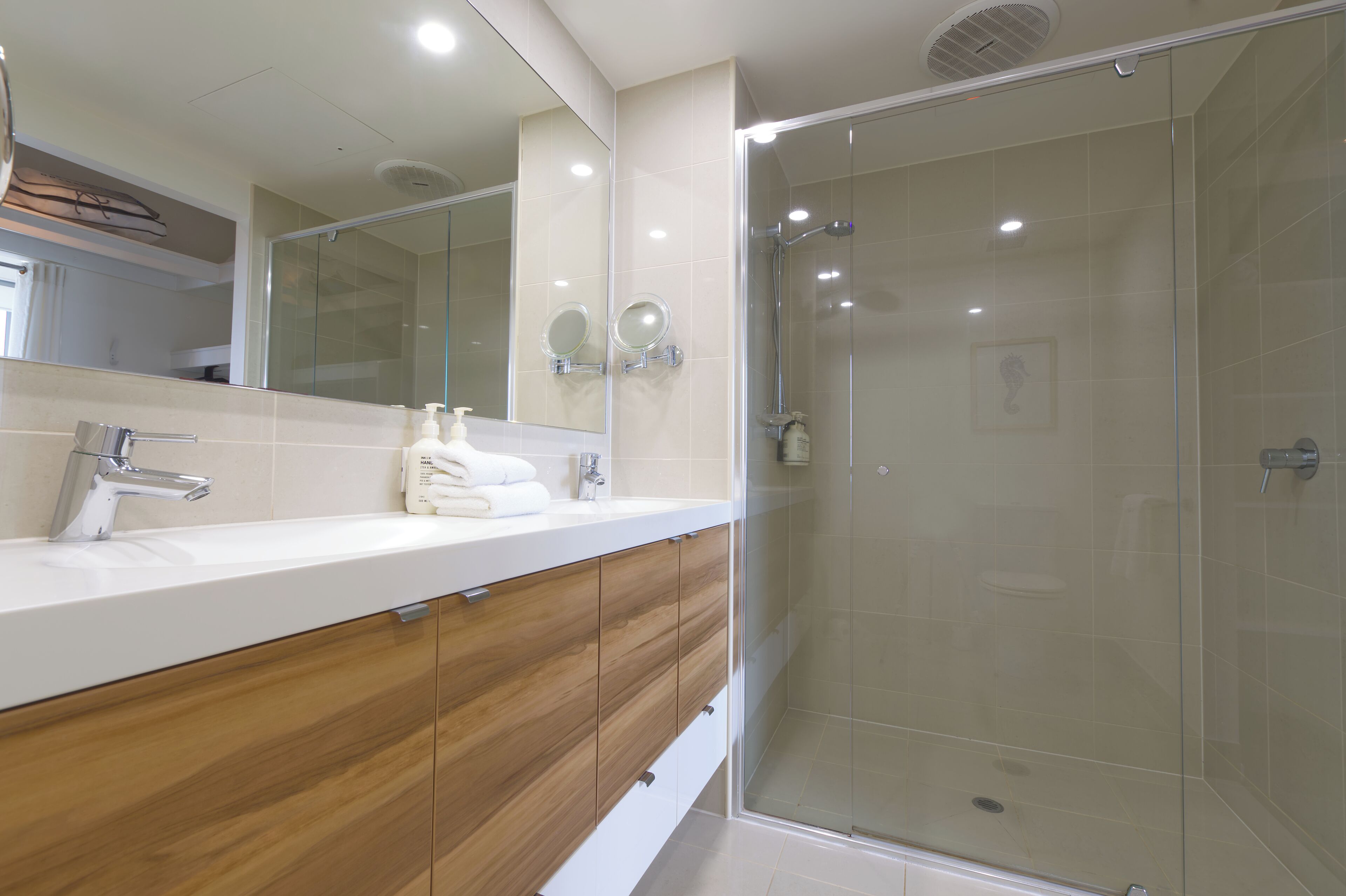 A modern bathroom with a glass-enclosed shower, a white sink with a chrome faucet, and wooden cabinetry.