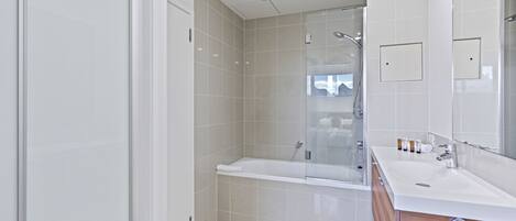 A modern bathroom with a glass-enclosed shower, a white sink, and a wooden vanity.