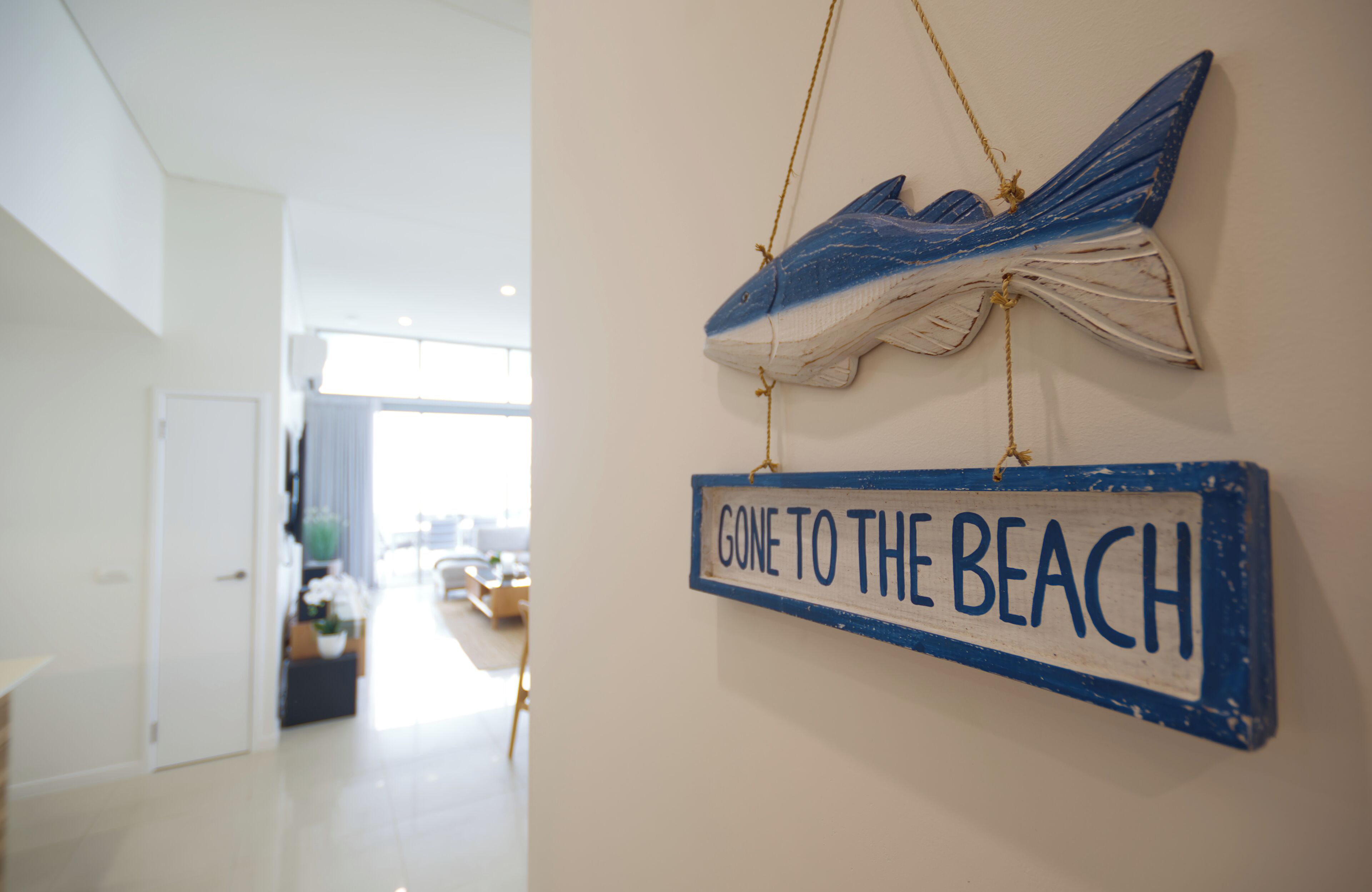 A hallway with a sign reading "GONE TO THE BEACH" and a decorative fish hanging above it.