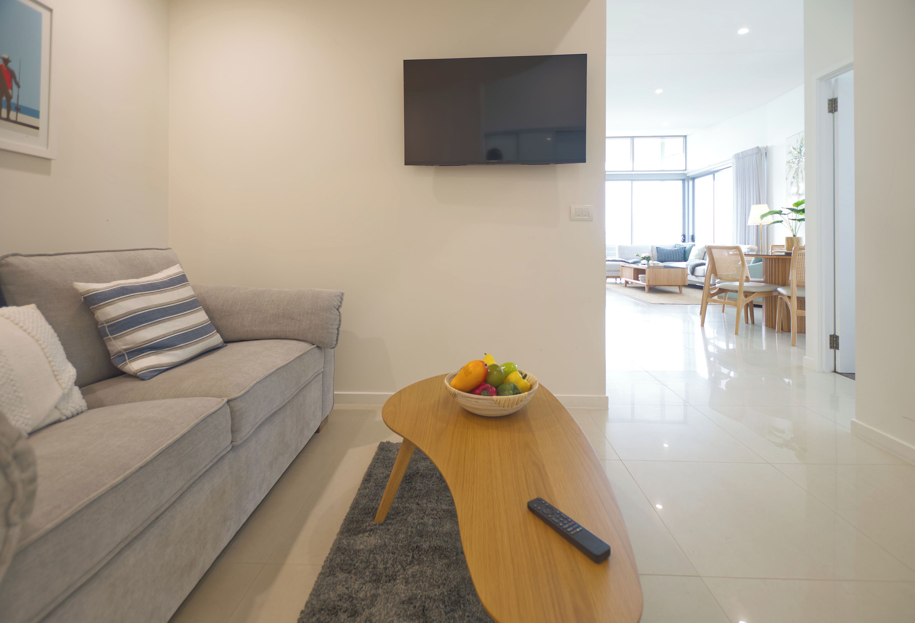 Un salon moderne avec un canapé, une table basse et un téléviseur fixé au mur.