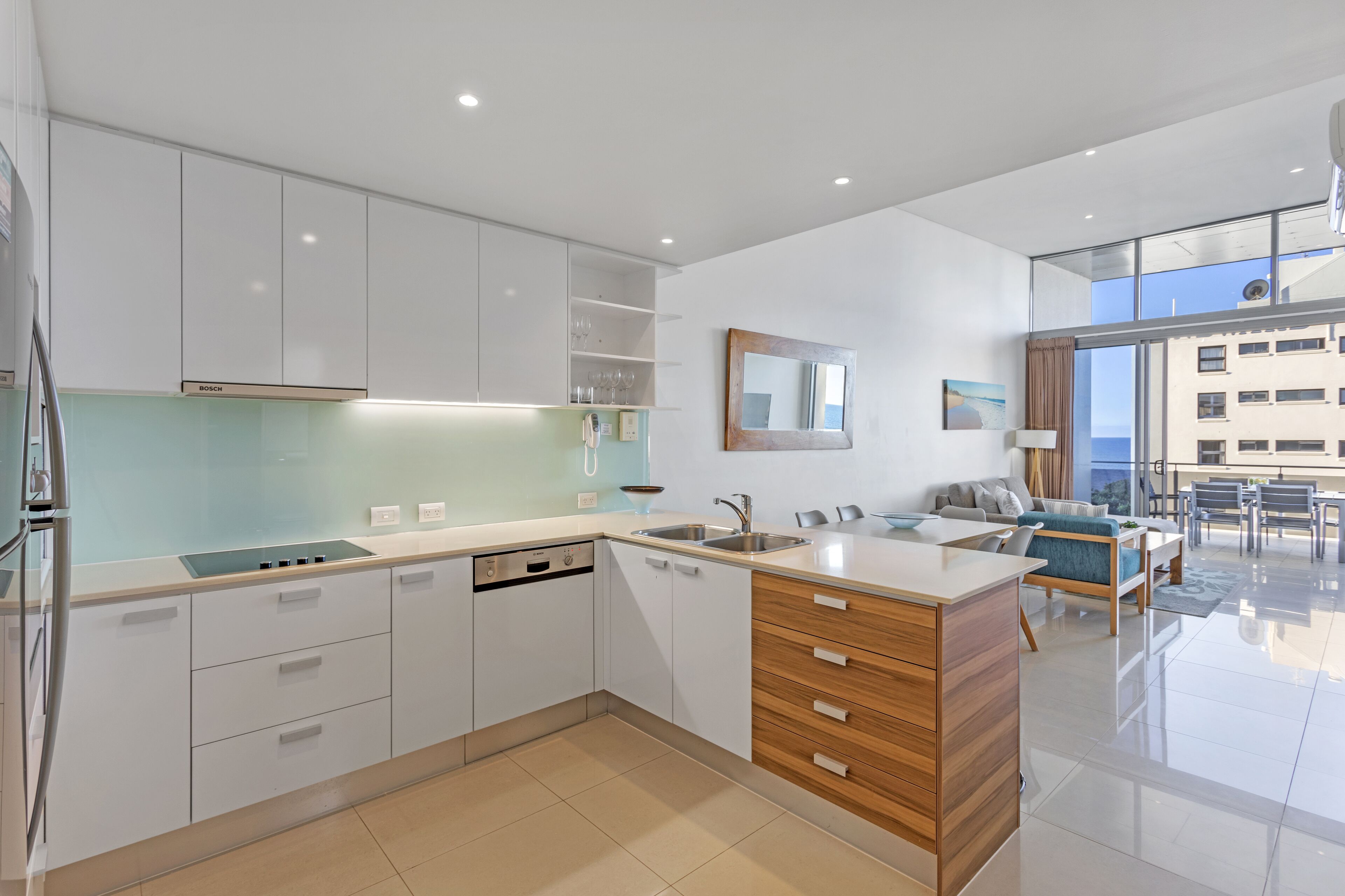 A modern kitchen with white cabinets, a Bosch dishwasher, and a wooden island.