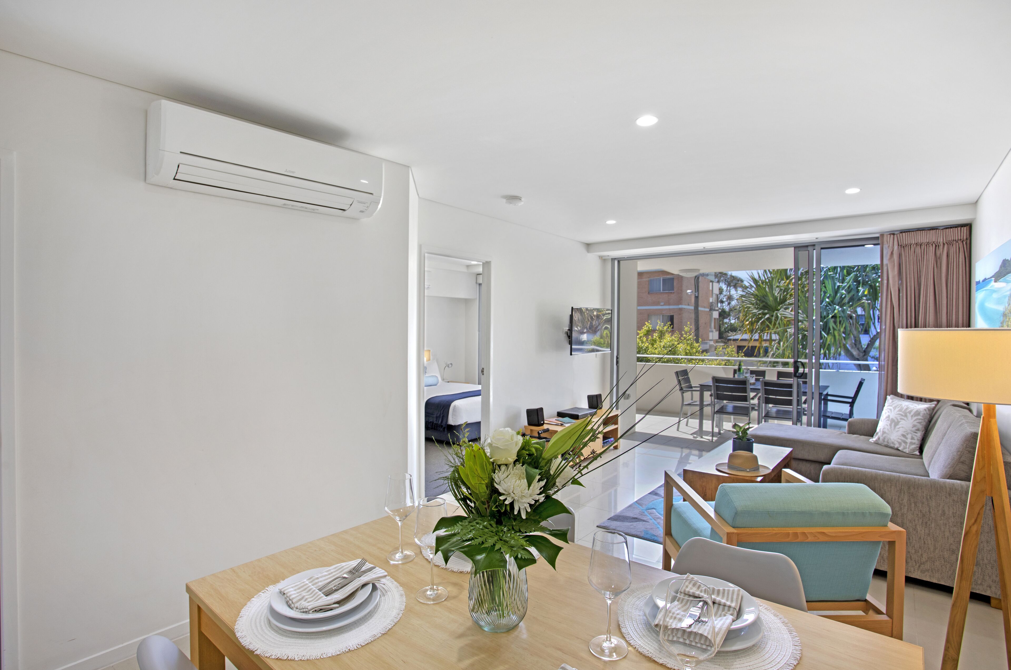 A modern living room with a dining area, a sofa, a coffee table, and a view of the outdoors.