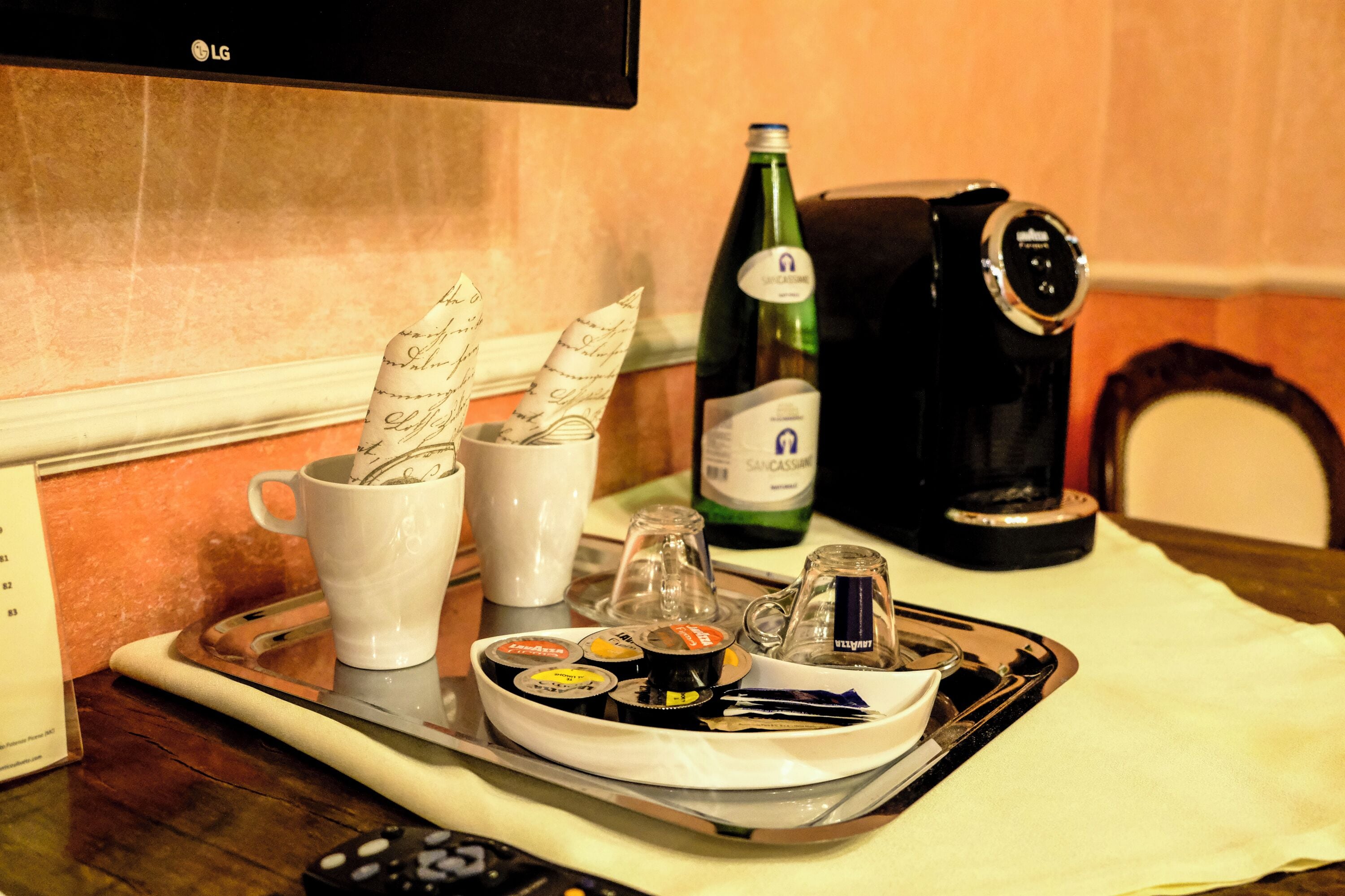 A tray with a coffee maker, a bottle of champagne, a cup, and condiments on a table.
