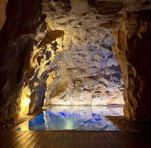 An interior view of a cave with a reflective pool at the bottom. - L'Antico Uliveto (Potenza Picena)
