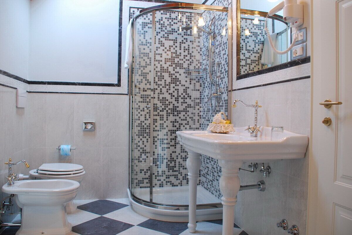 Un baño con ducha compartimentada con vidrio, un lavamanos blanco y un inodoro.