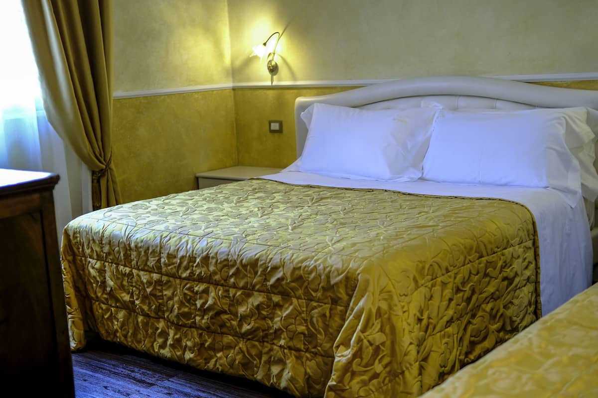 Ein Hotelzimmer mit einem Bett, einem Nachttisch und einer Wandlampe.