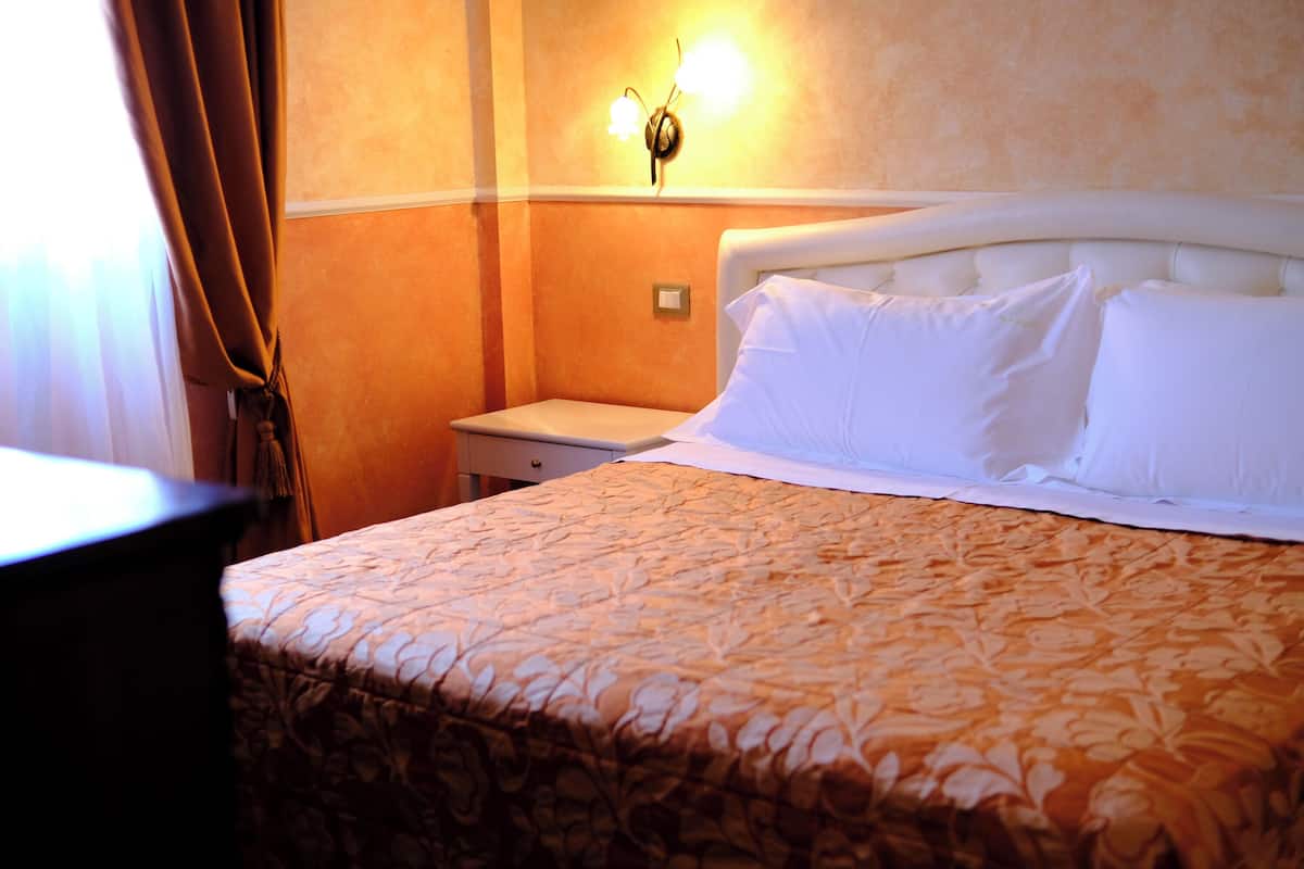 Ein Hotelzimmer mit einem Bett, einem Nachttisch und einer Wandleuchte.