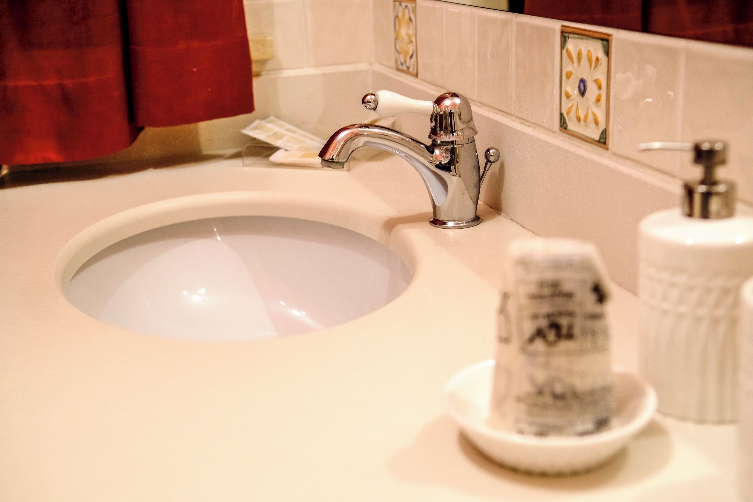 A bathroom sink with a chrome faucet, a soap dispenser, and a soap dish.