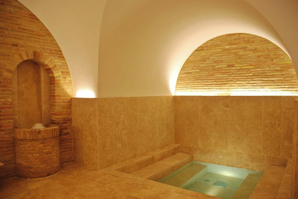 Ein Spa-Raum mit einer Steinbadewanne, einer Ziegelwand und einer Holzbank.