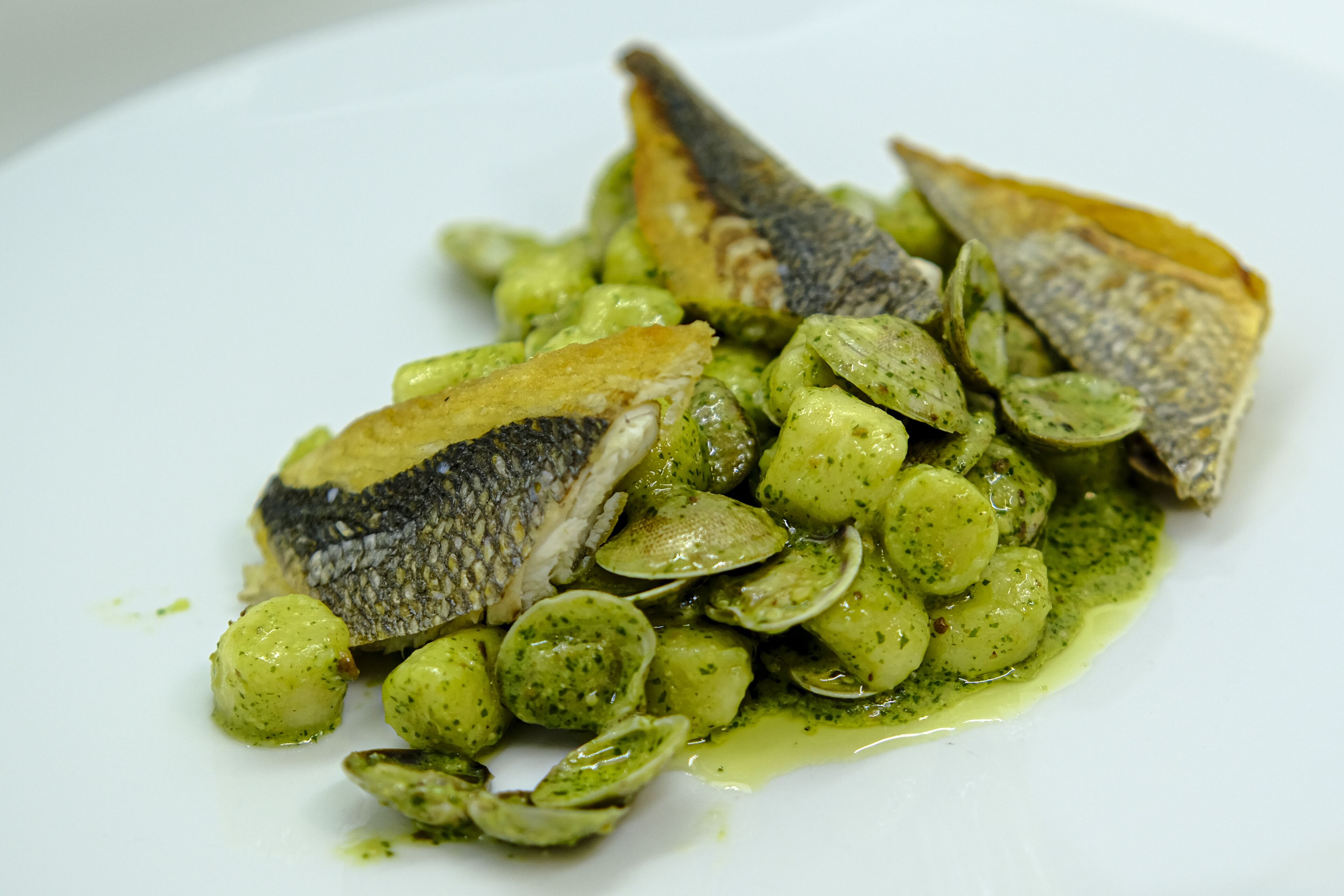 Un plato de comida con pescado y verduras verdes.