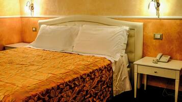 Quarto de hotel com uma cama, mesa de cabeceira com telefone e luminárias fixadas na parede.