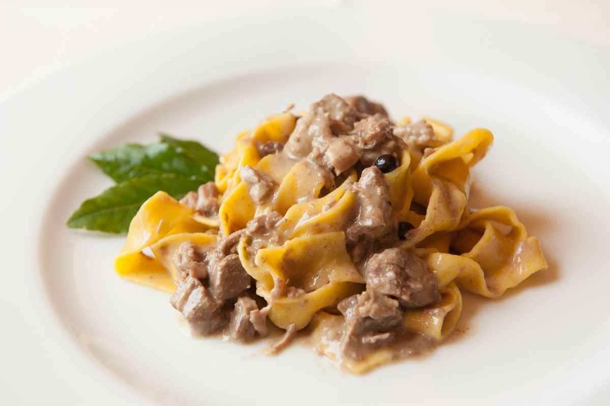 A plate of pasta with a creamy sauce and meat.