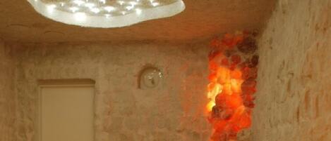 Un cuarto de spa con paredes de piedra, una lámpara en el techo y una puerta.