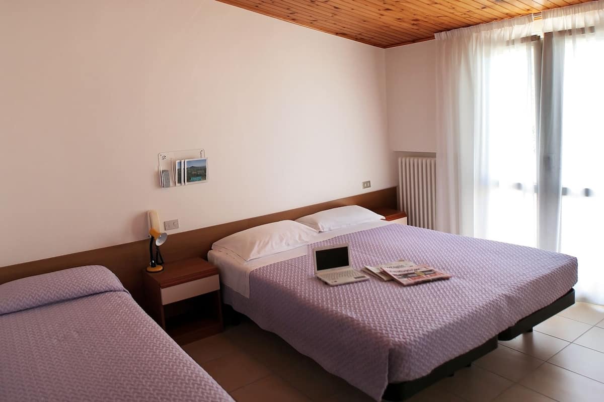 A hotel room with two beds, a laptop, and a nightstand with a lamp.