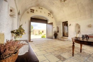 Un interno con pavimento in pietra, un arco e vista sull'esterno.