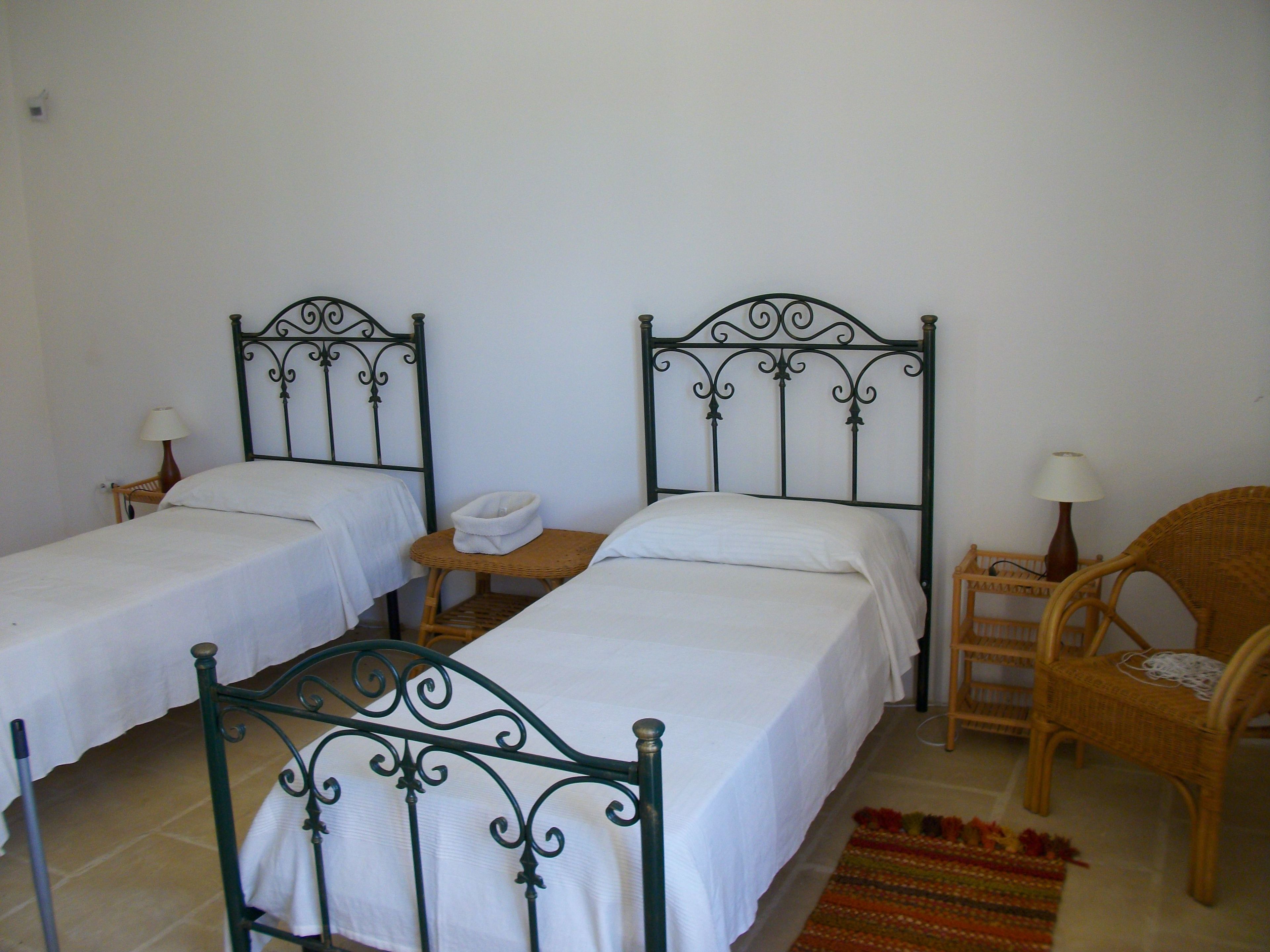 Una habitación con dos camas individuales, una mesita, dos sillas y un tapete estampado.