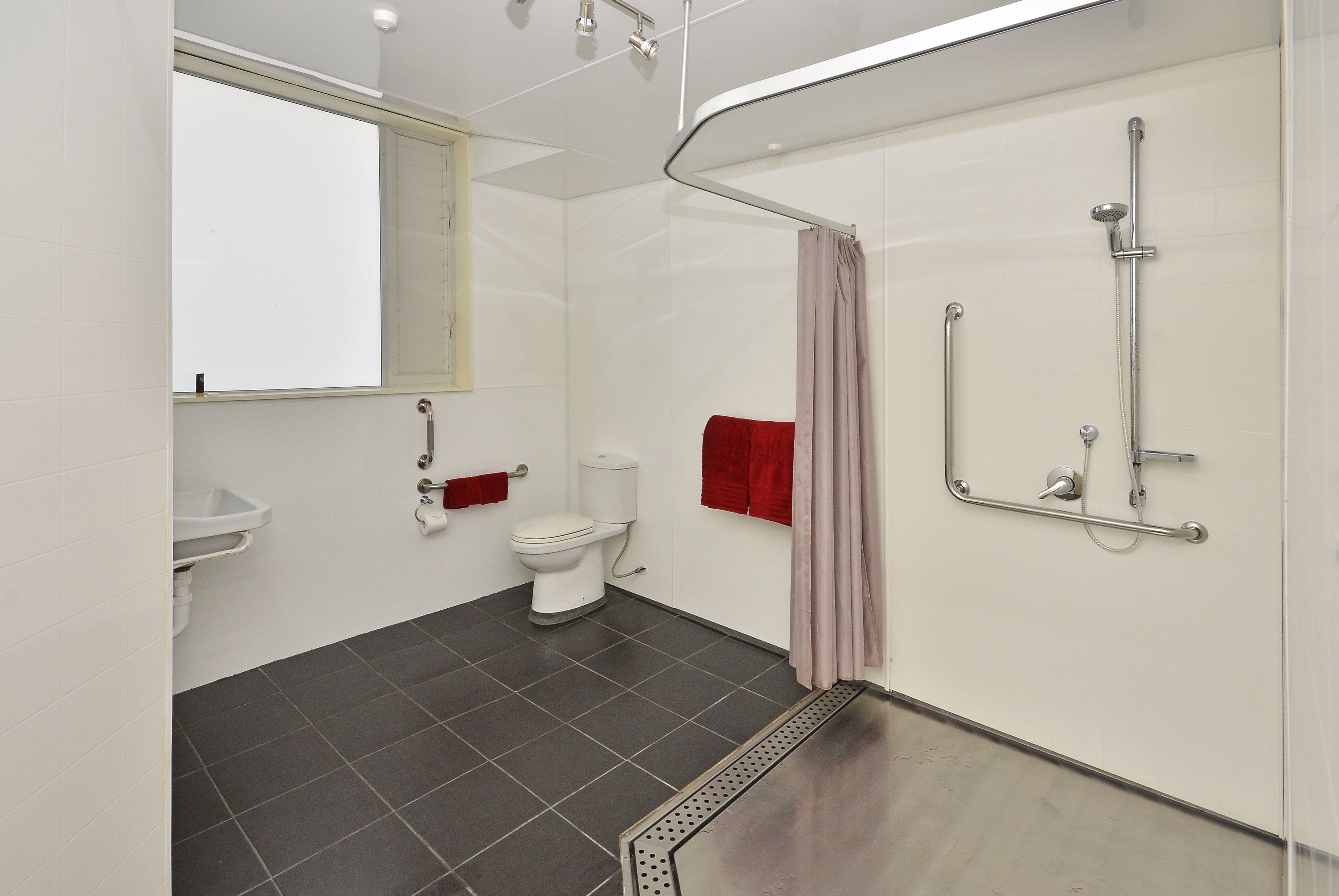 A modern bathroom with a toilet, sink, shower, and a window.