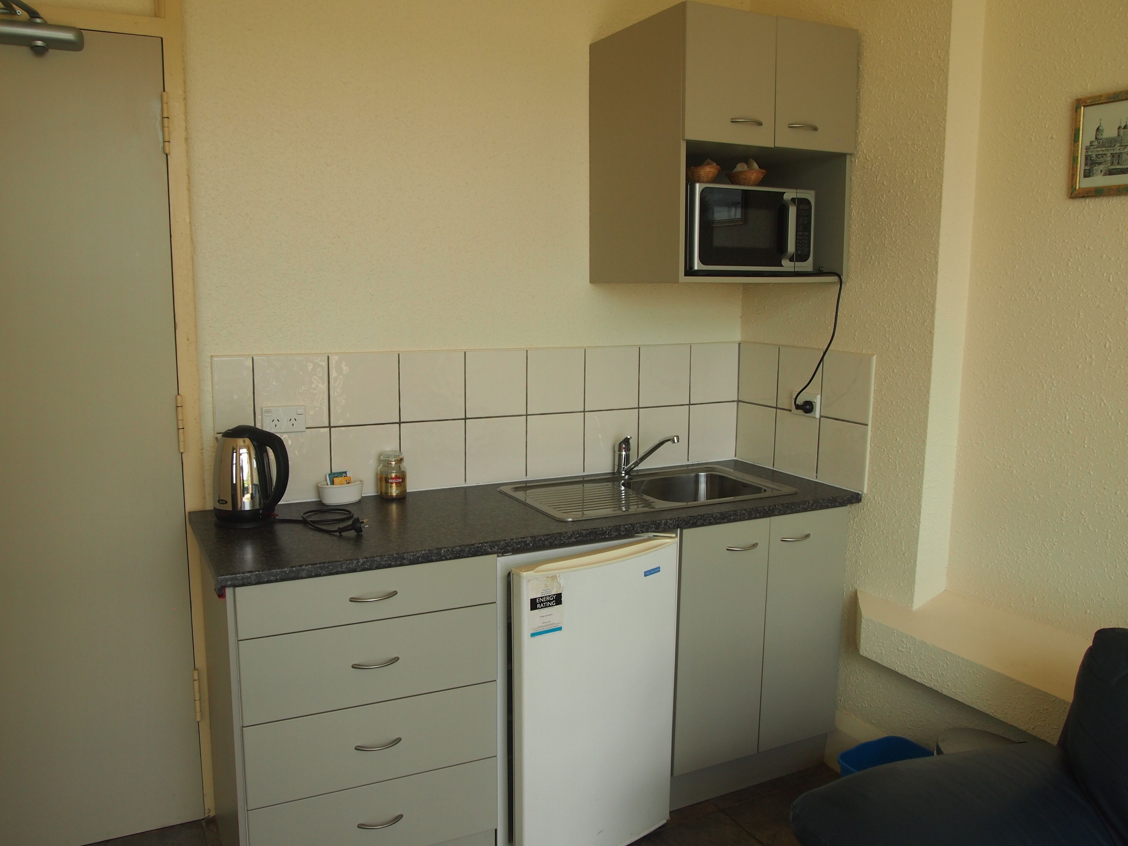 A compact kitchen with a built-in microwave, a sink, and a refrigerator.