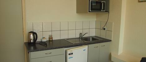 A compact kitchen with a built-in microwave, a sink, and a refrigerator.