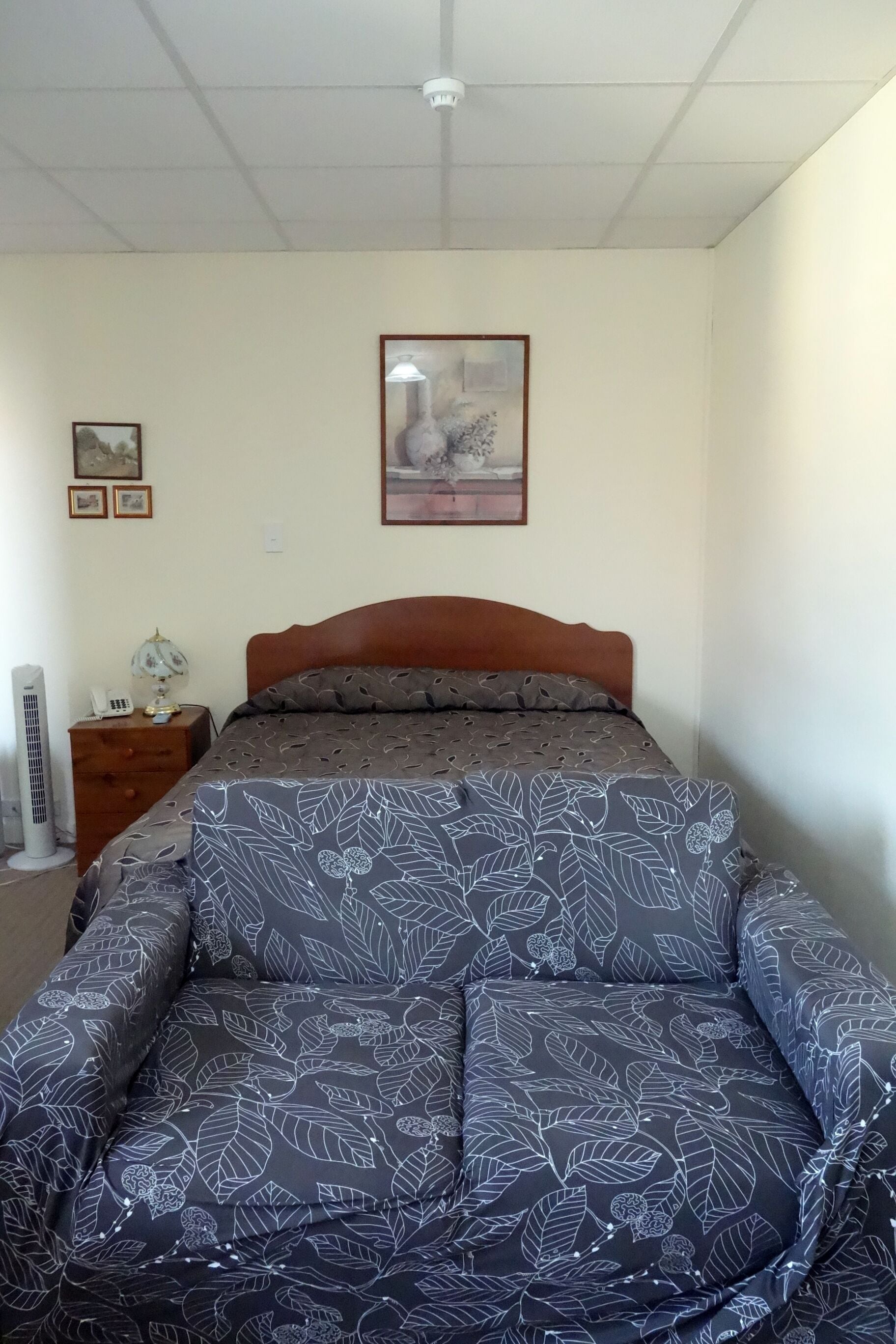 A bedroom with a bed, a nightstand, a lamp, and a framed picture on the wall.