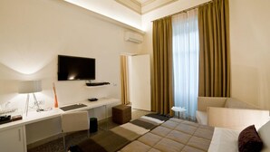 A hotel room with a bed, a desk, a TV, a chair, and a window with curtains. - Town House Cavour (Reggio Calabria)
