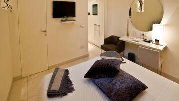 A hotel room with a bed, a desk, a chair, a television, and a mirror.