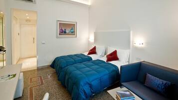 A hotel room with two beds, a sofa, a desk, and a painting on the wall.