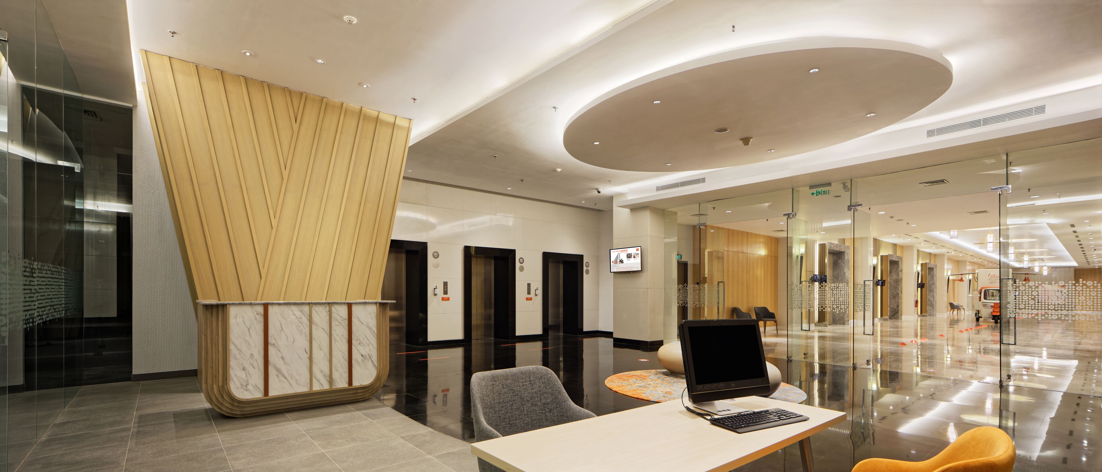 Un moderno vestíbulo de hotel con mostrador de recepción, zona de estar y ascensores.
