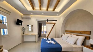 Une chambre à coucher moderne avec un lit, des tables de chevet, un bureau et un téléviseur.