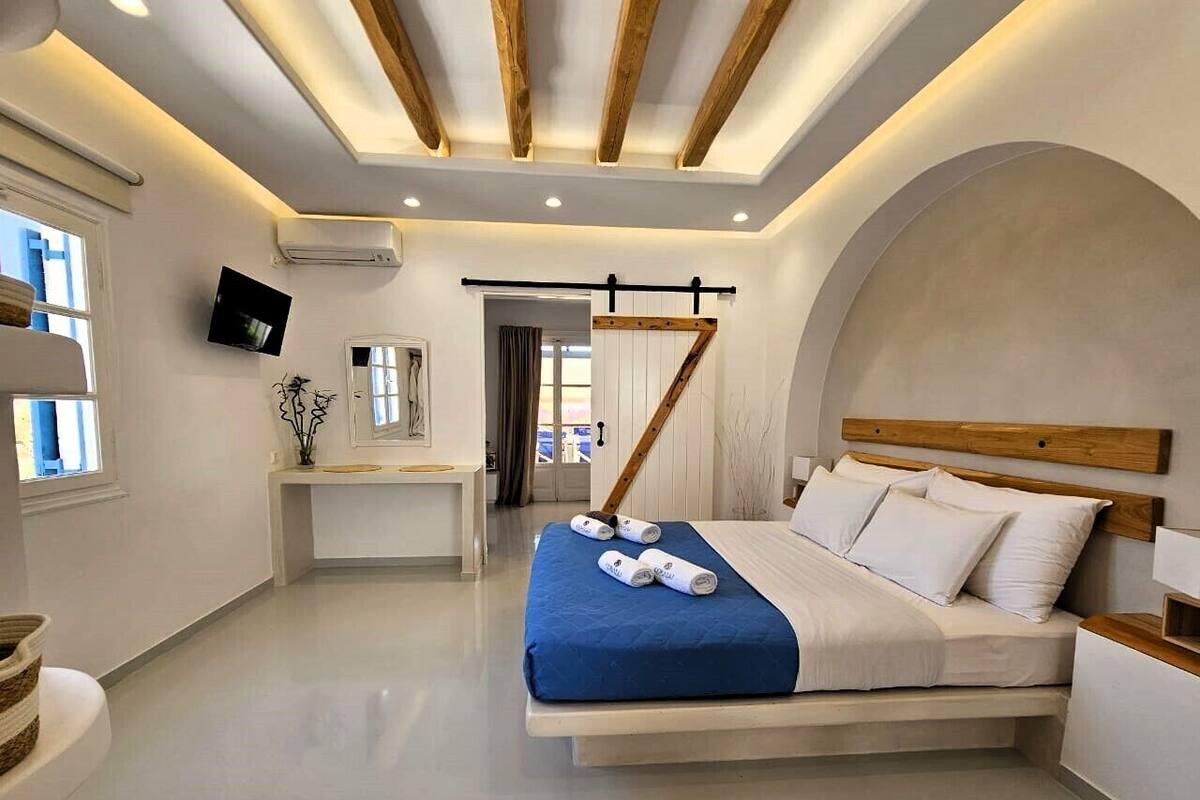 A modern bedroom with a bed, bedside tables, a desk, and a TV.