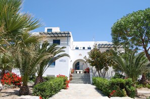 A white building with a blue door and a sign reading "Coralli". - Coralli Beach Apartments (Naxos)