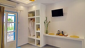 Une salle de bain moderne équipée d’une douche, d’une étagère intégrée pour les articles de toilette, d’un téléviseur fixé au mur et d’une fenêtre avec des rideaux.