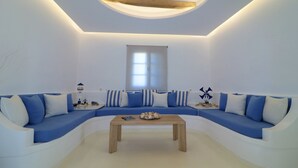 Un salon moderne avec un canapé bleu aux lignes courbes, une table basse en bois et une grande fenêtre laissant entrer la lumière naturelle.