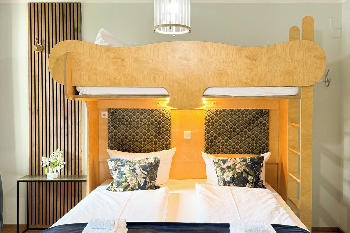 A modern hotel room with a large bed, wooden headboard, and a ceiling mural.