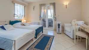 A bedroom with two beds, a desk, a chair, a heater, and a sliding glass door to a balcony.