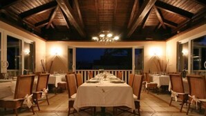 An indoor dining area with a long table set for a meal, surrounded by chairs.