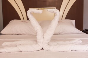 Una cama con toallas blancas dispuestas en forma de corazón.
