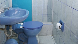 Un bagno con lavandino, water e box doccia blu.