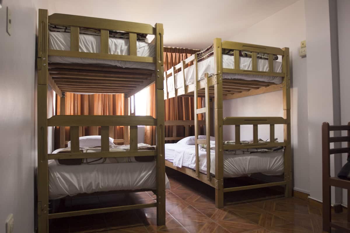 Una habitación con literas, cabeceros de madera y suelo de baldosas.
