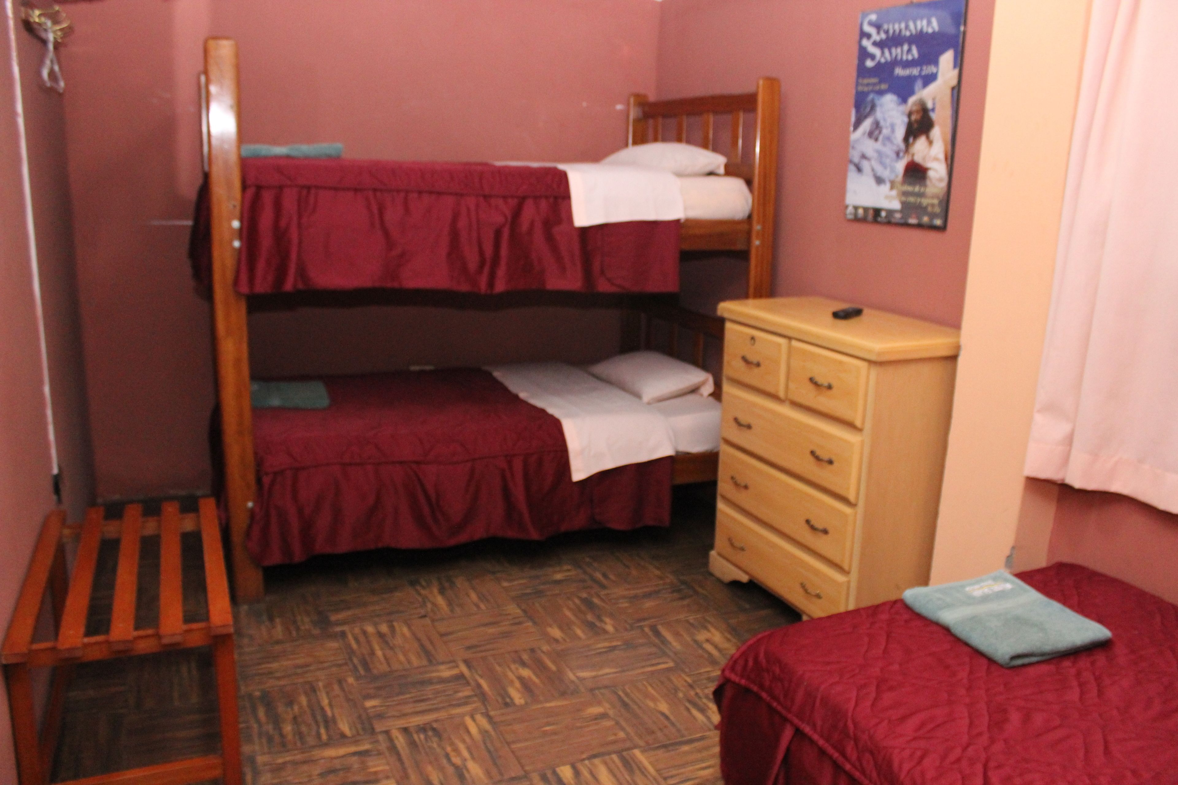 Una habitación tipo dormitorio con literas, un aparador de madera y un cartel en la pared.