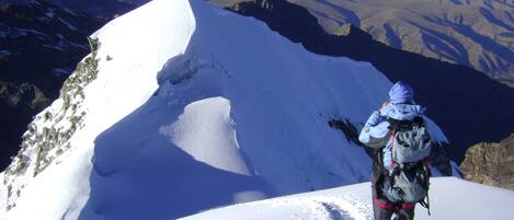 A person standing on a snow-covered mountain peak with a clear view of the surrounding landscape.