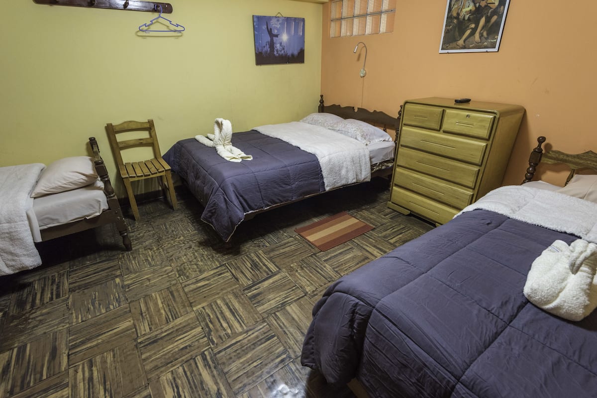 A room with two beds, a wooden chair, a dresser, and a wall-mounted towel rack.