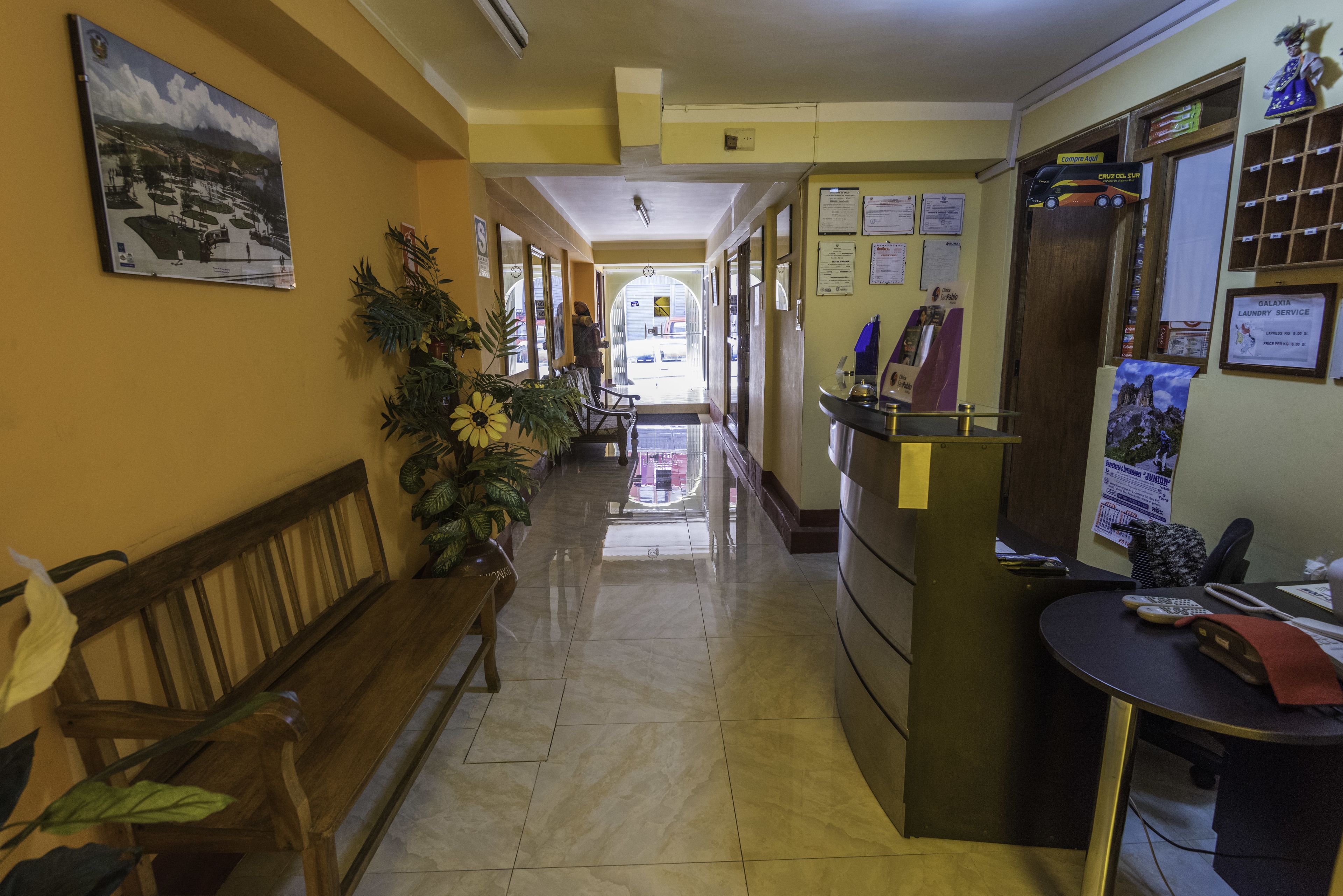 A hallway with a wooden bench, a reception desk, and a view into the lobby area.