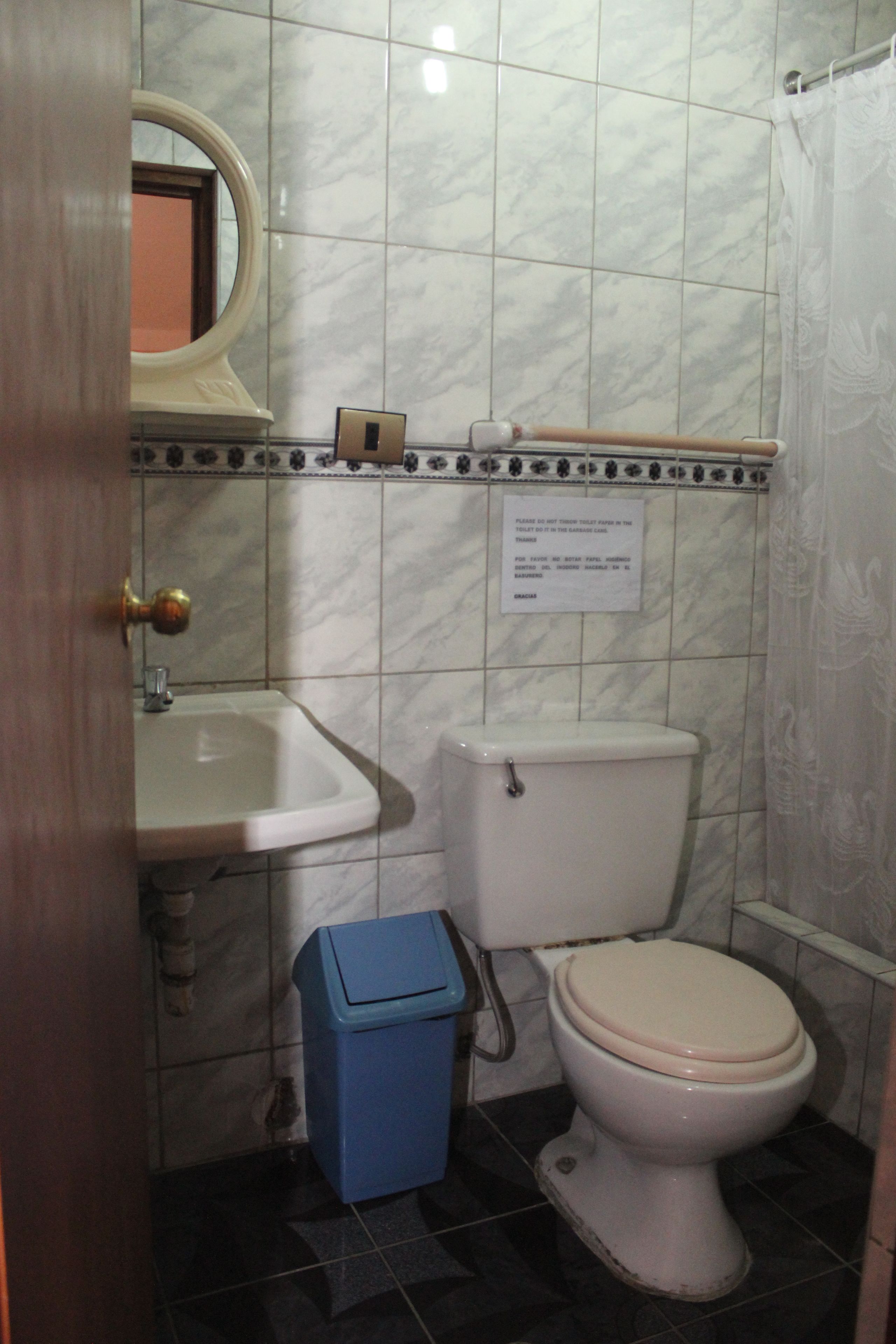 A bathroom with a toilet, sink, and a blue trash bin.