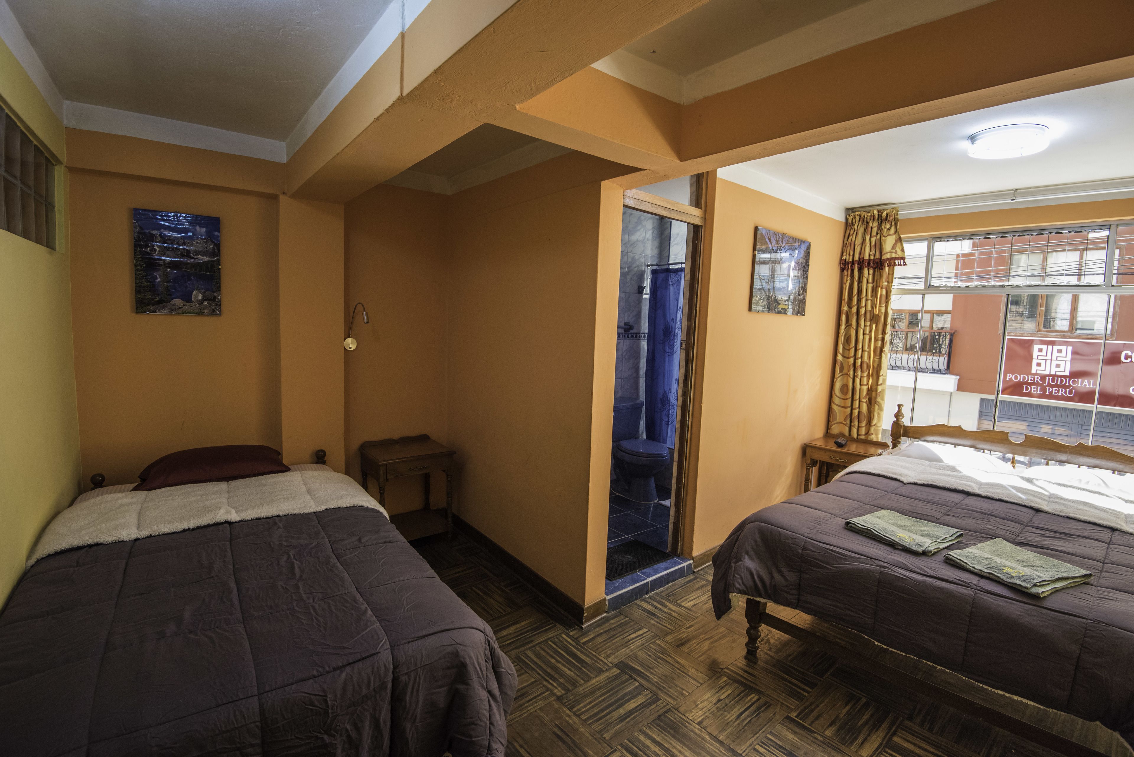 Een hotelkamer met twee bedden, een kleine tafel en een deur naar de badkamer.