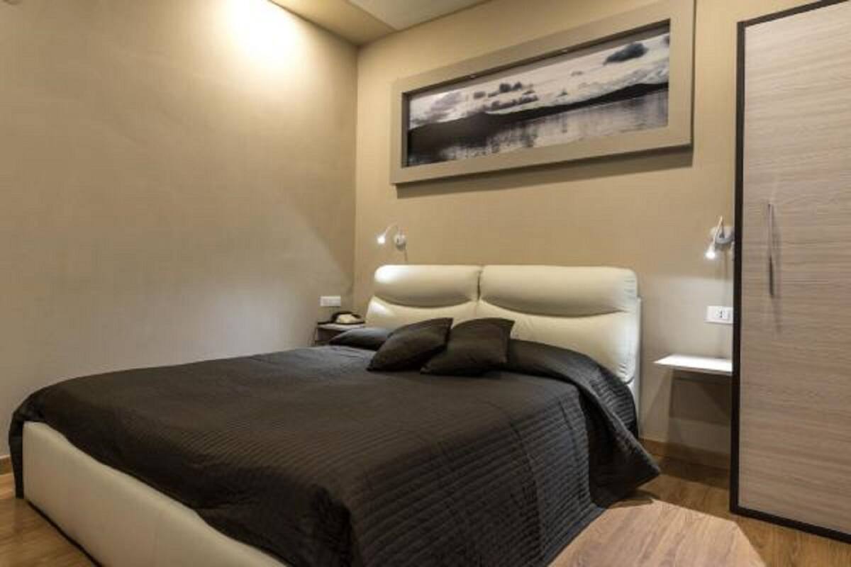 A bedroom with a bed, a nightstand, a wardrobe, and a framed picture on the wall.