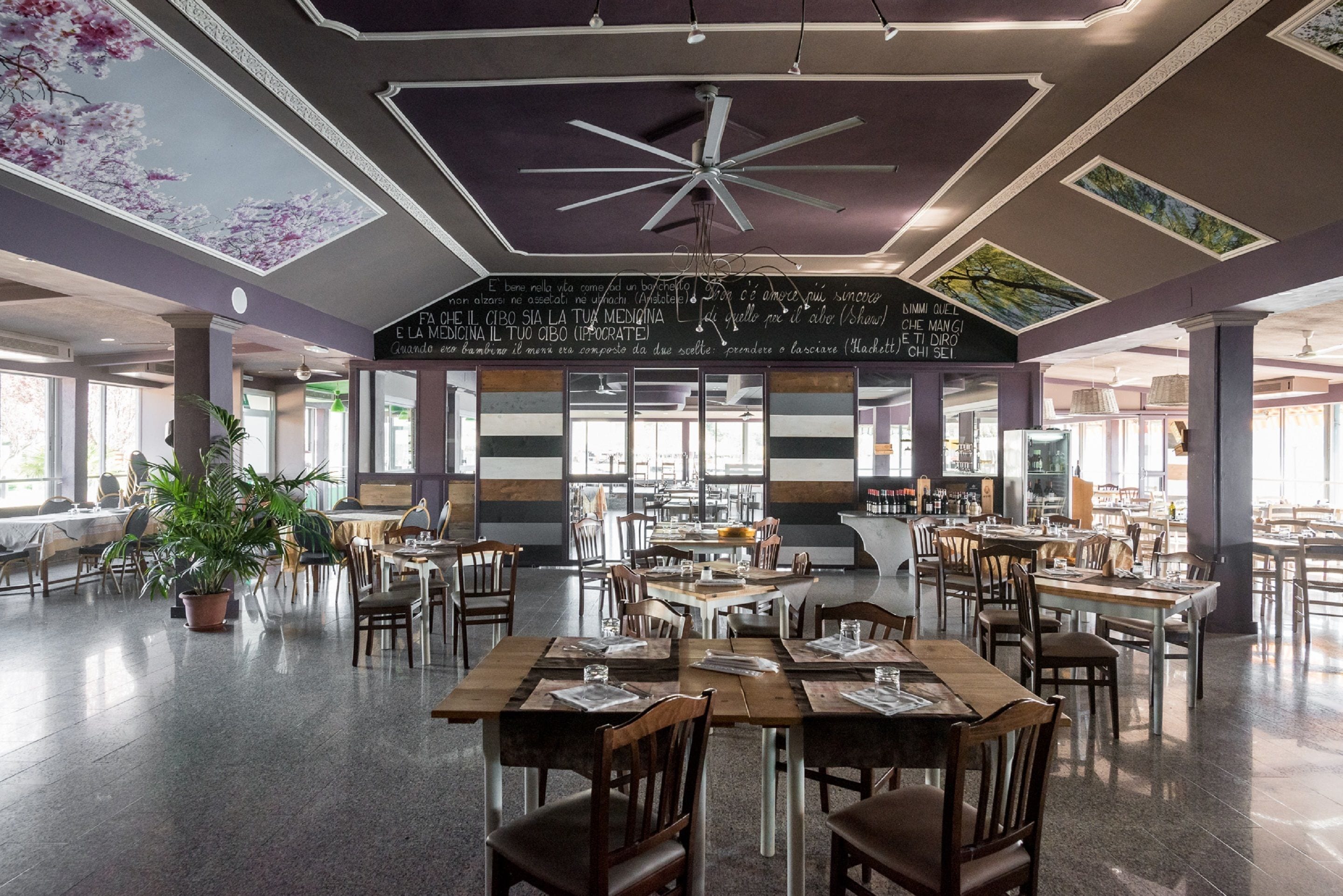 Ein geräumiges Restaurant mit hohen Decken, moderner Beleuchtung und einer zentralen Sitzgruppe.