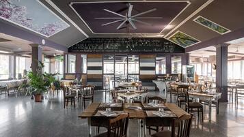 Ein geräumiges Restaurant mit hohen Decken, moderner Beleuchtung und einer zentralen Sitzgruppe.