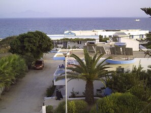 A coastal hotel with a view of the sea, a parking area, and a sign advertising Sunday roast. - Haralambos Studios (Kos)