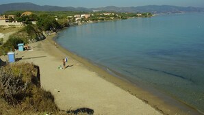 A beach with clear water, a few people, and buildings in the background. - Kavos Psarou Studios and Apartments (Zakynthos)